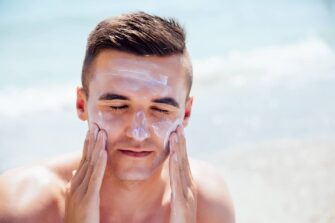 Man putting on sunscreen that may contain Benzene